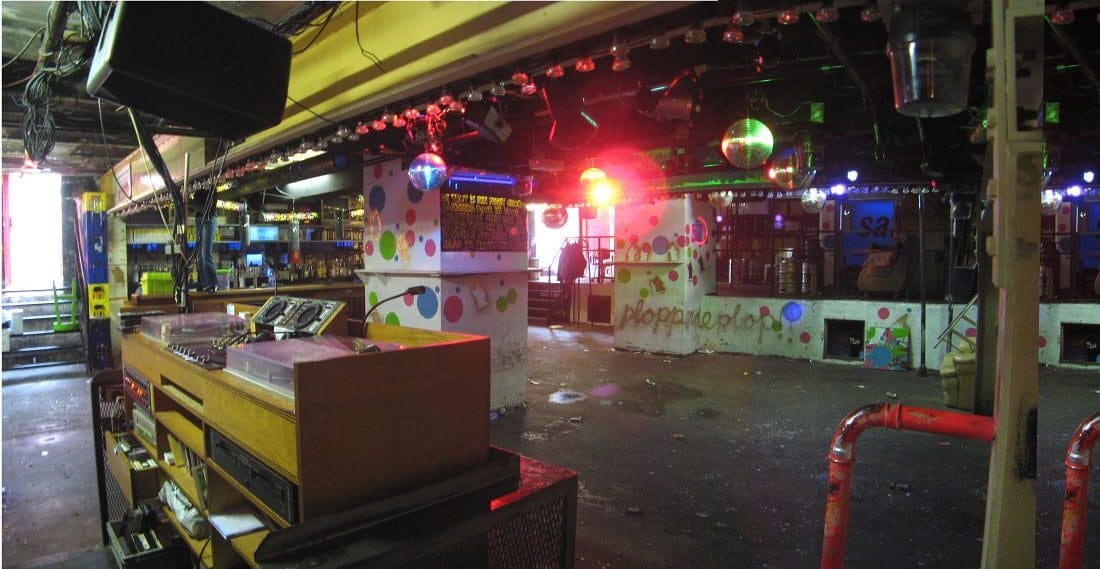 Une scène de vie nocturne gay vibrante à Amsterdam avec des lumières éblouissantes dans un club.