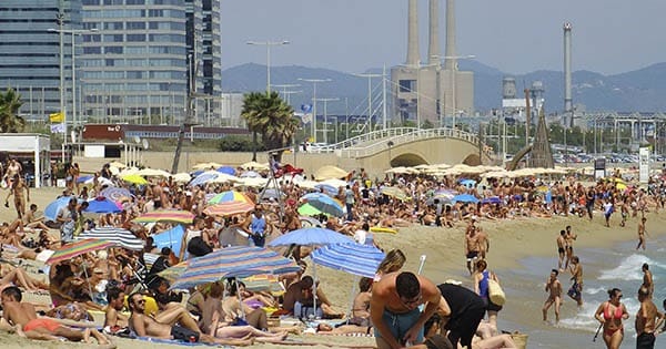 Une plage bondée avec de nombreuses personnes et des parasols.