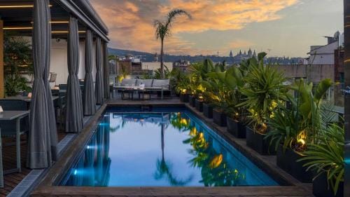 Une piscine sur le toit avec vue sur la ville au crépuscule, située dans un hôtel gay-friendly à Barcelone.