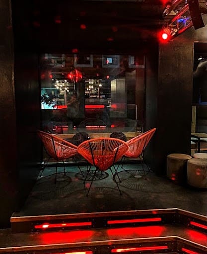 Une pièce sombre avec des lumières rouges et des chaises, parfaite pour les bars et les clubs de Munich gay-friendly.