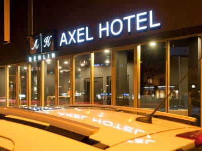 Hôtel Axel à Berlin la nuit avec une voiture garée devant, présenté dans le Guide gay de Berlin.