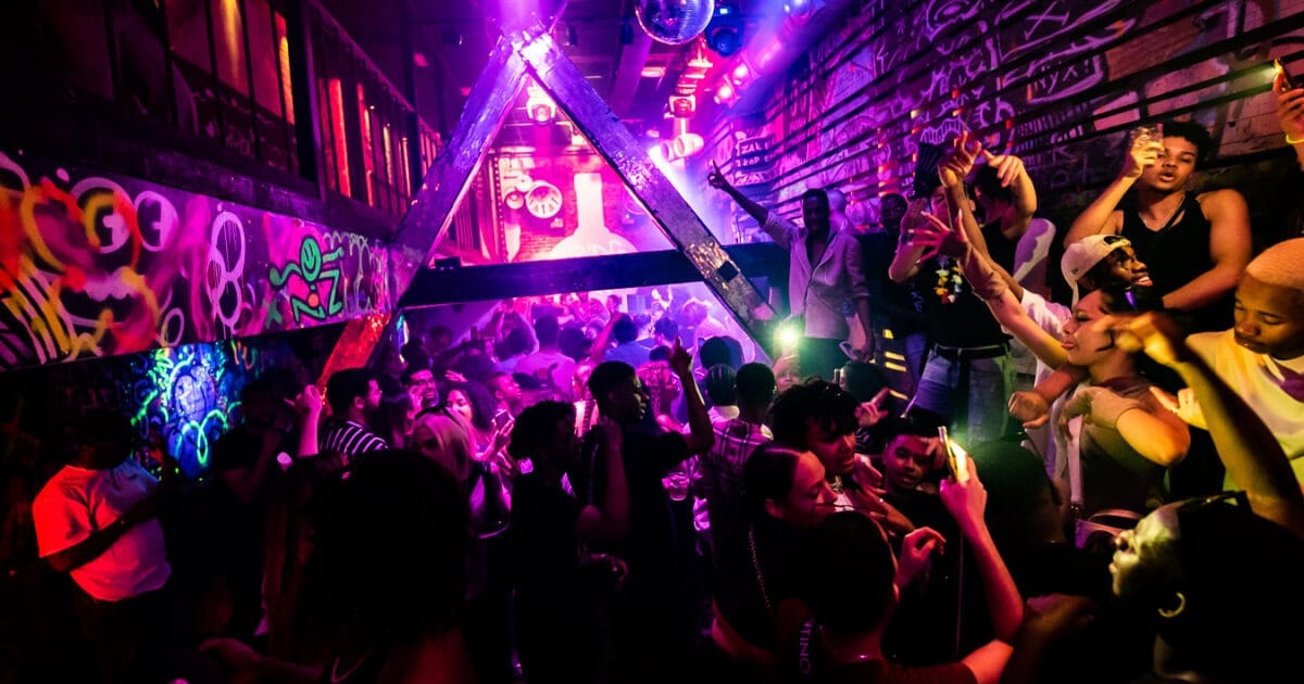 Une foule de personnes dans une boîte de nuit animée à Amsterdam, mettant en lumière la scène de voyage gay de la ville.