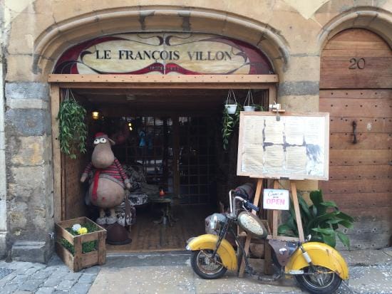 Un scooter jaune est garé devant un magasin à Lyon.