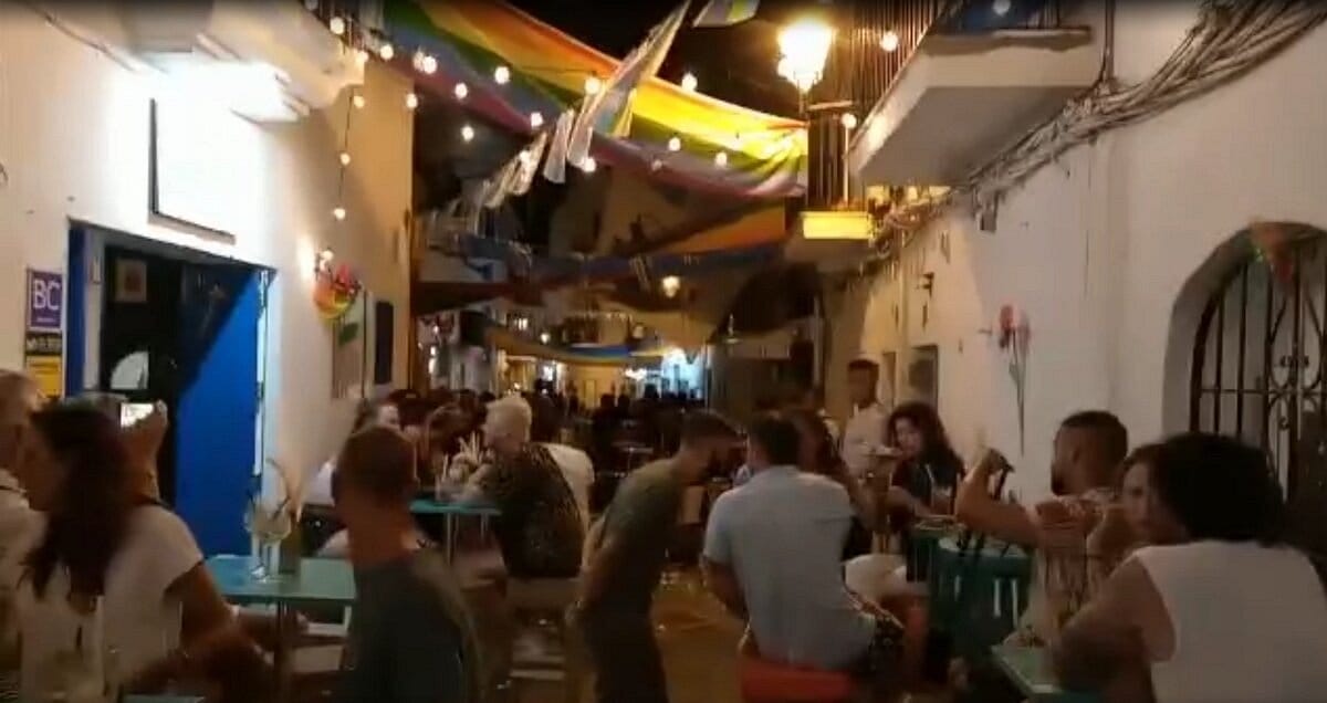 Un groupe de personnes assises à des tables dans une ruelle étroite.