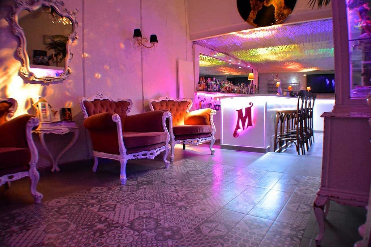 Un bar avec des lumières violettes et des chaises.